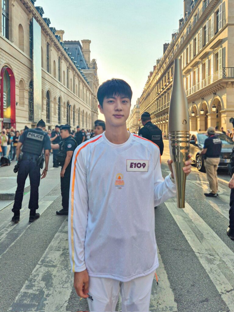 Jin (BTS) posant avec la torche olympique dans Paris 